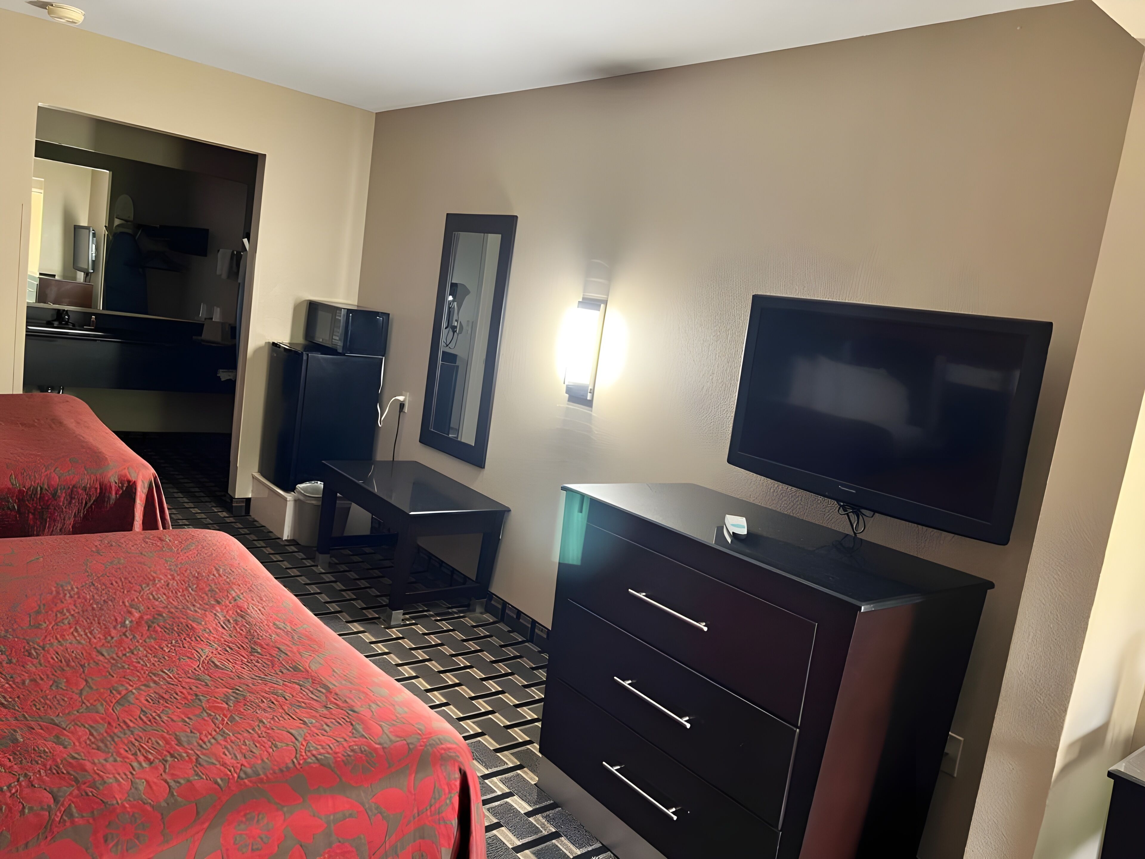 Una habitación de hotel con dos camas, un escritorio, un televisor y un minibar.