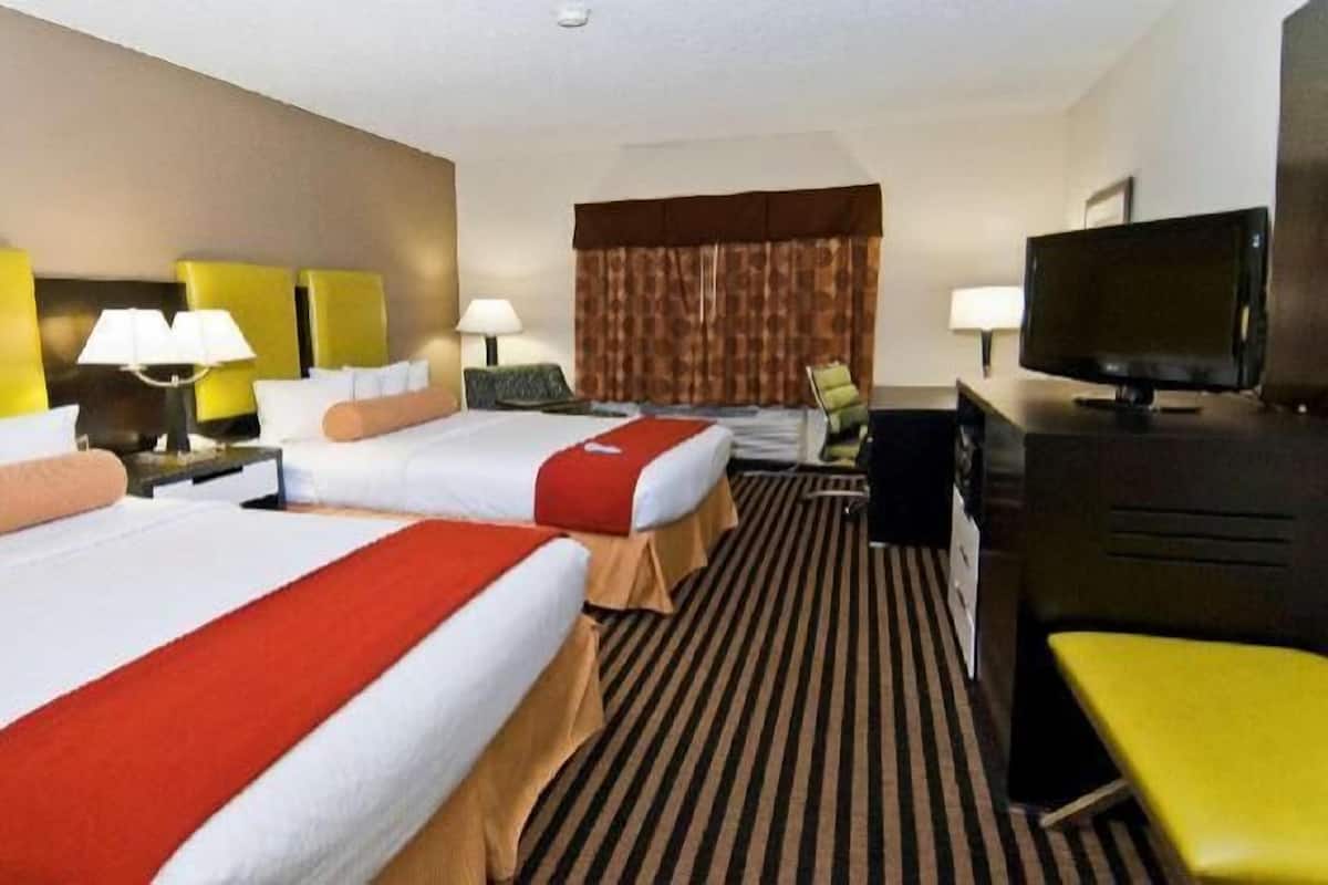 A hotel room with two beds, a TV, a desk, and a chair.