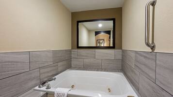 Une salle de bain moderne avec une grande baignoire, un miroir et une barre d’appui.