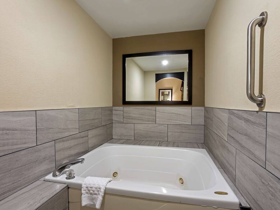 Une salle de bain moderne avec une grande baignoire, un miroir et une barre d’appui.
