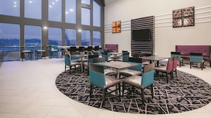 Un espacio interior amplio con ventanas grandes, varias opciones de asientos y una alfombra estampada.