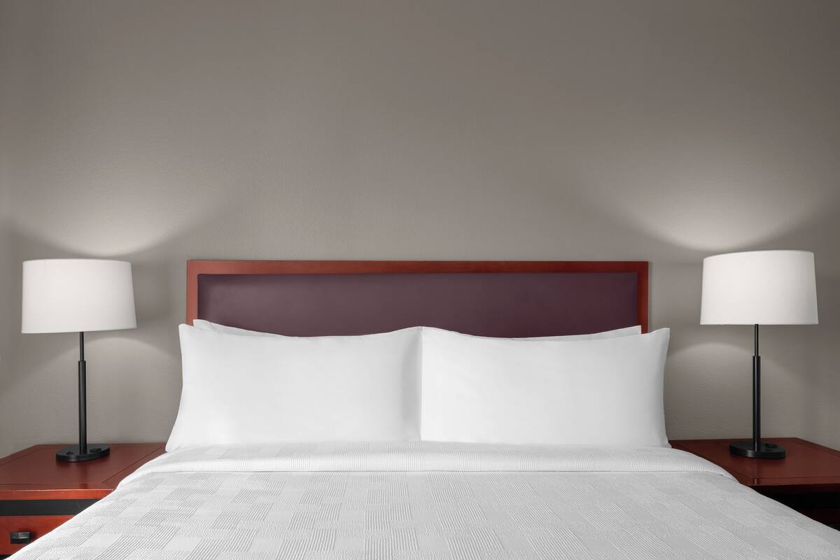 Een hotelkamer met een groot bed, twee nachtkastjes en twee lampen.