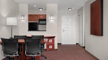 A conference room with a table, chairs, a lamp, and a kitchenette in the background.