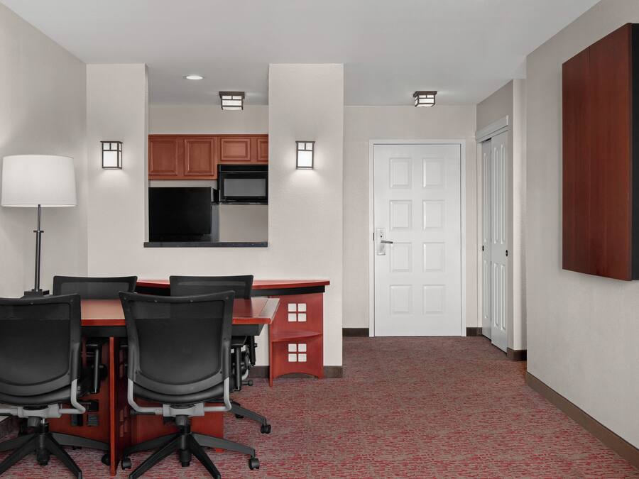 A conference room with a table, chairs, a lamp, and a kitchenette in the background.