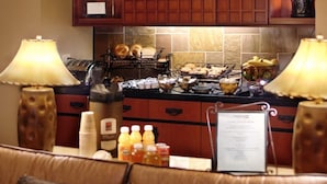 Un buffet de petit-déjeuner proposant divers plats et boissons, un panneau affichant le menu et une lampe décorative.