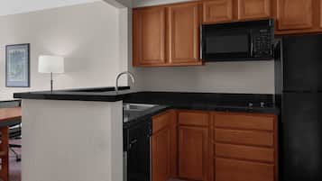 Una cocina moderna con armarios de madera, un microondas negro y un refrigerador negro.
