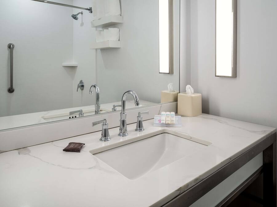 Een moderne badkamer met een grote spiegel, twee wasbakken en een douche.