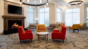 A spacious lobby with a fireplace, comfortable seating, large windows, and a modern chandelier. - Hilton Garden Inn Folsom (Folsom)
