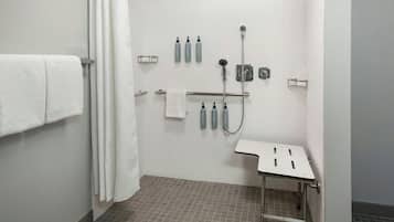 A bathroom with a shower, a sink, and a towel rack.