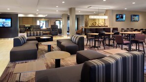 A modern hotel lobby with a seating area, a bar, and a TV screen. - Courtyard by Marriott Milpitas Silicon Valley (Milpitas)