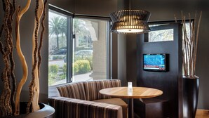 Un intérieur moderne comprenant un coin salon, une table ronde, un téléviseur et des éléments décoratifs.