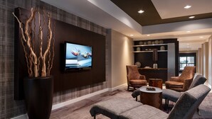 Un salon moderne doté d’un téléviseur à écran plat, de sièges confortables et d’œuvres d’art décoratives murales.