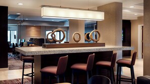 Un espace bar moderne avec un comptoir en granit, des tabourets de bar et des anneaux décoratifs sur le mur.