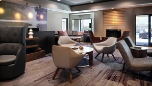Un espace de détente moderne, doté de sièges confortables, d’une cheminée et de grandes fenêtres offrant une vue imprenable.