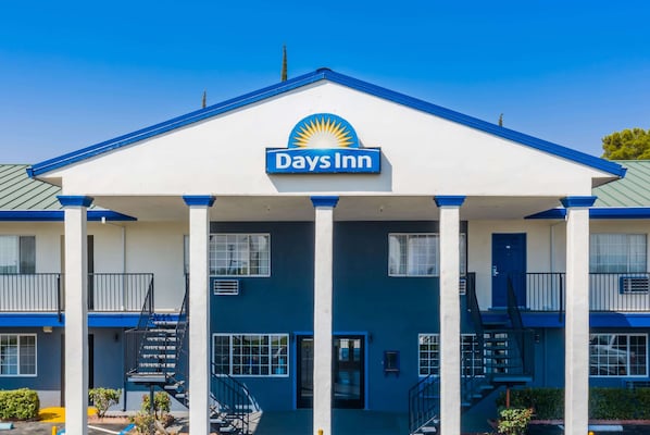 A Days Inn building with a prominent sun logo, a central entrance with a covered porch, and multiple balconies.
