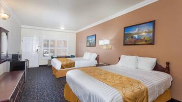 A hotel room with two beds, a desk, a mirror, and a door leading to a balcony.