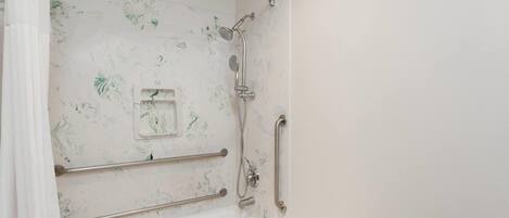 A bathroom with a shower, grab bars, and a white bathtub.