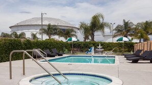 A swimming pool with lounge chairs, a hot tub, and a large dome structure in the background. - Days Inn & Suites by Wyndham South Gate (South Gate)