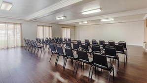 A conference room with rows of chairs, large windows with curtains, and recessed ceiling lights. - Days Inn & Suites by Wyndham South Gate (South Gate)