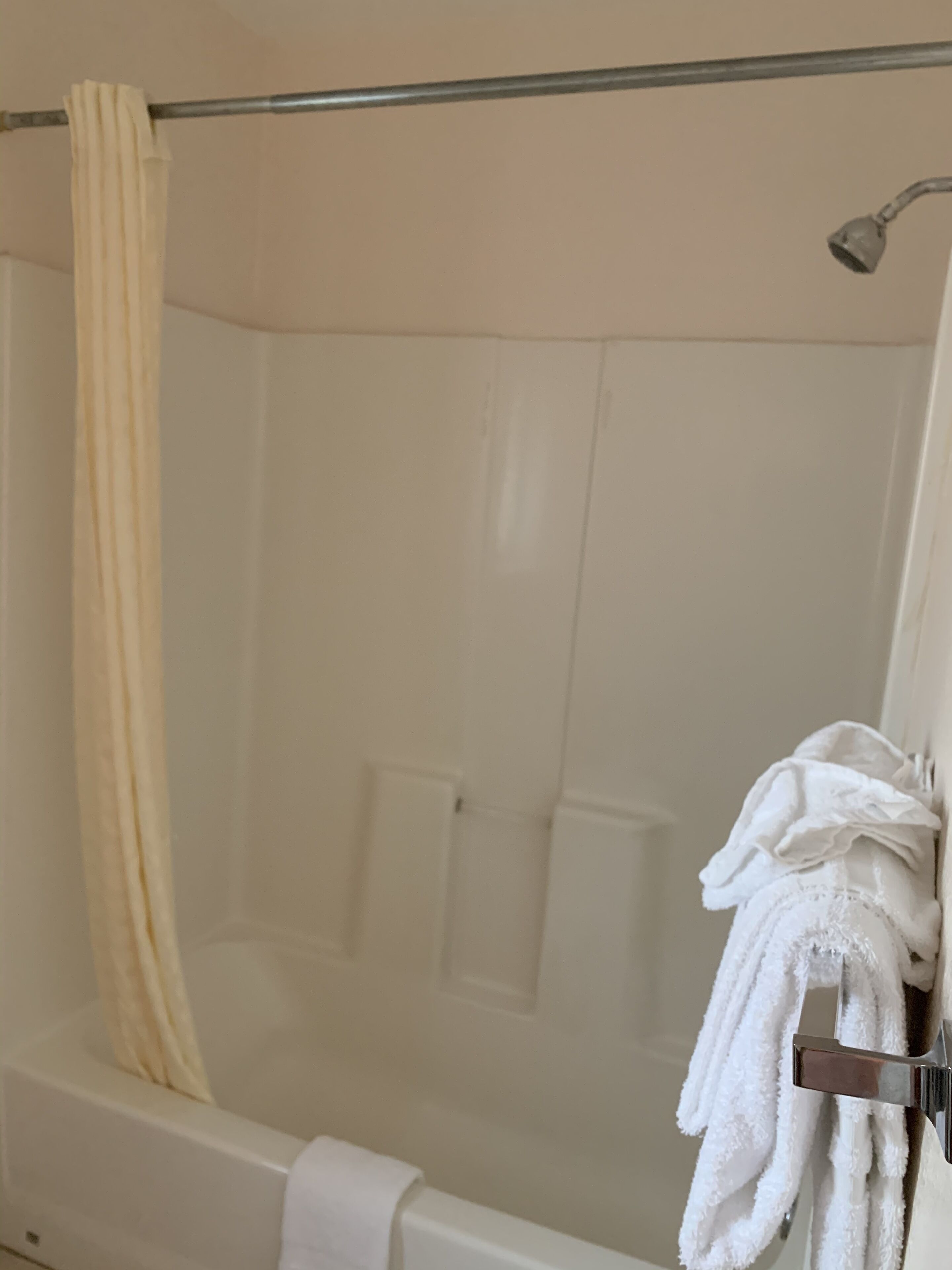 Ein Badezimmer mit einer Duschkabine, einem Handtuchhalter mit Handtüchern und einem Duschvorhang.