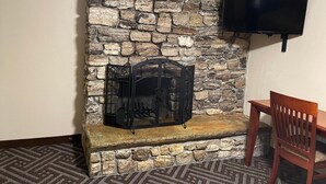 A stone fireplace with a TV mounted above it, a wooden bench, and a patterned rug on the floor. - Tahoe Hacienda Inn (South Lake Tahoe)