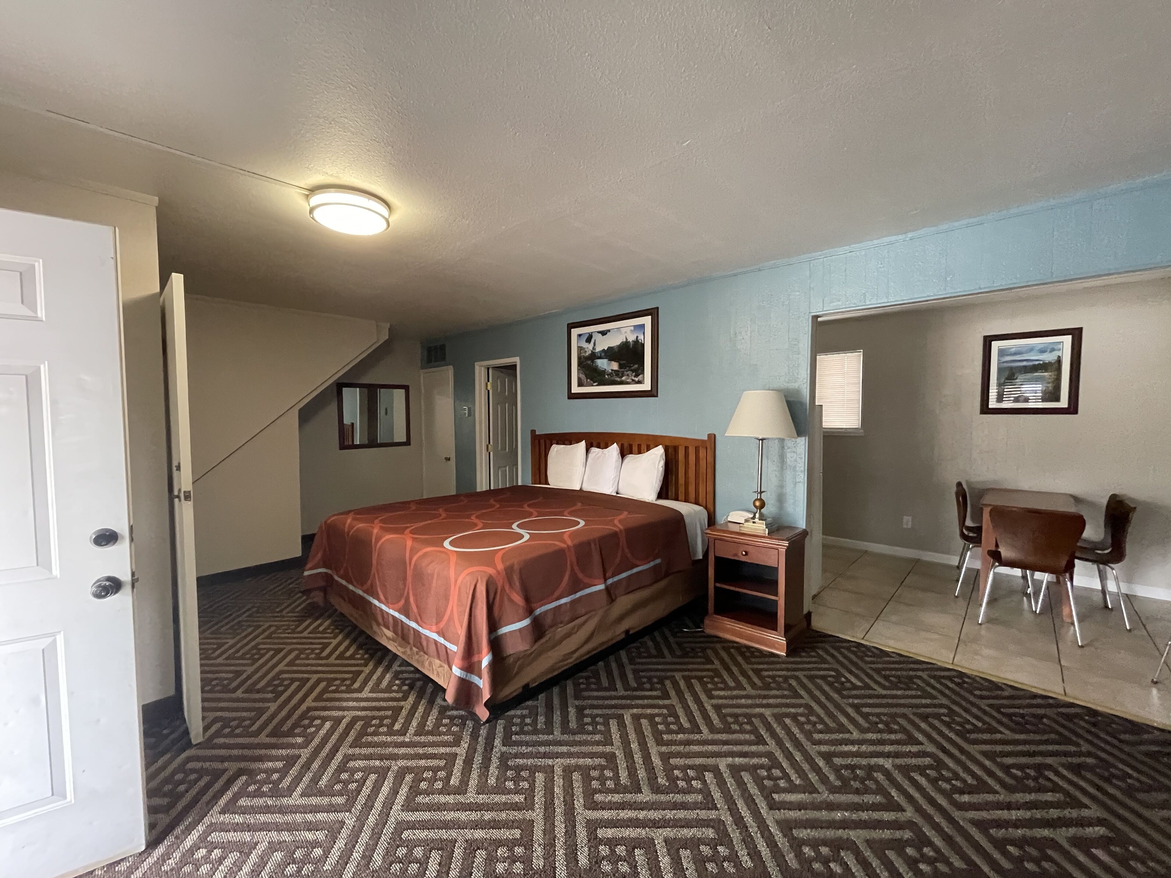 Una habitación de hotel con cama, escritorio, silla y una escalera.