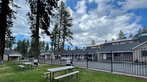 A fenced outdoor area with picnic tables and a building complex in the background. - Tahoe Hacienda Inn (South Lake Tahoe)