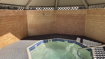 Relax in a hot tub surrounded by a covered structure with a metal ladder for easy access.