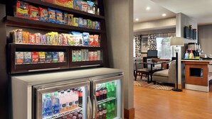 A hotel lobby with snack shelves, a refrigerator with beverages, and a seating area. - Hampton Inn Tracy (Tracy)