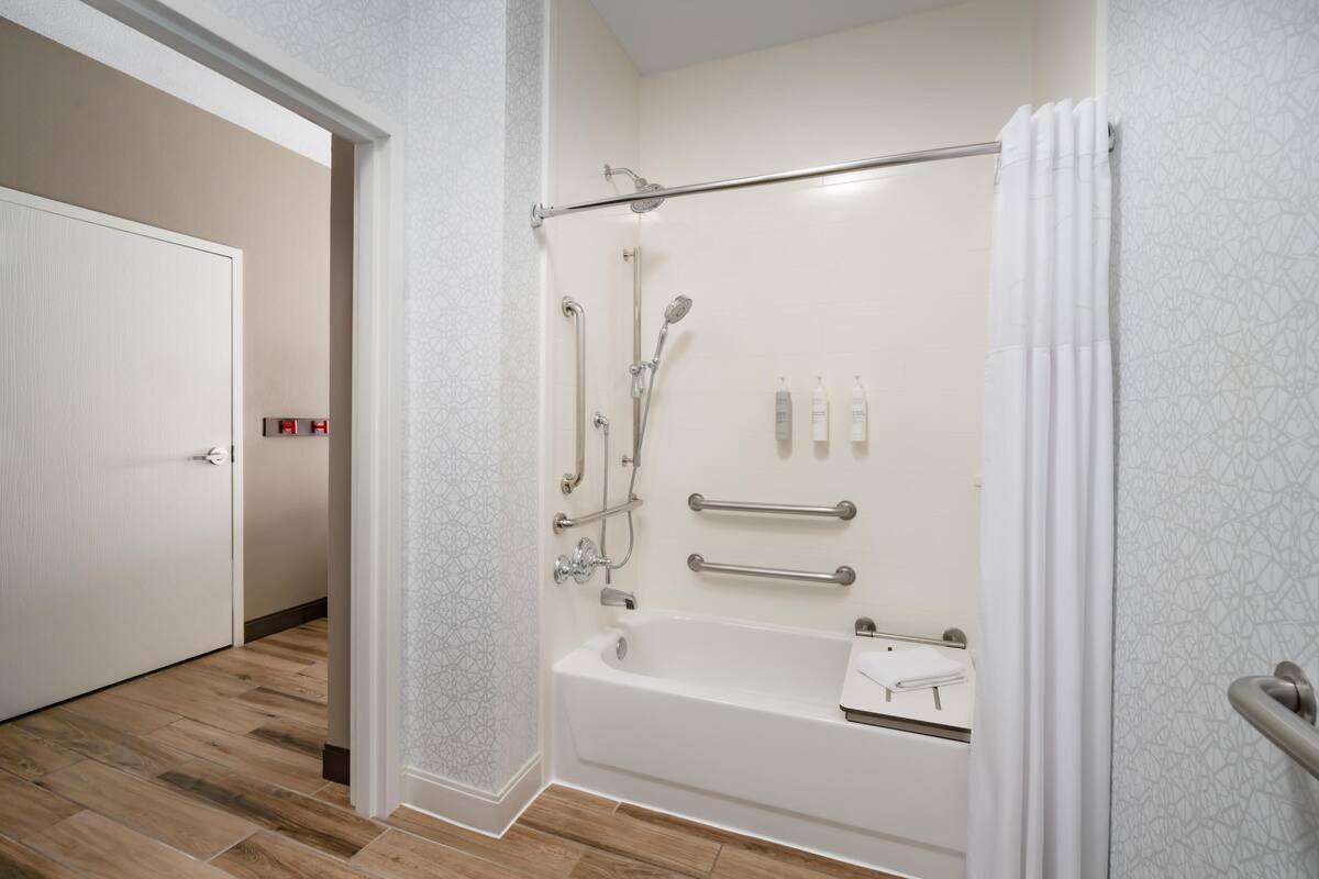 A modern bathroom with a shower, grab bars, and a bathtub.