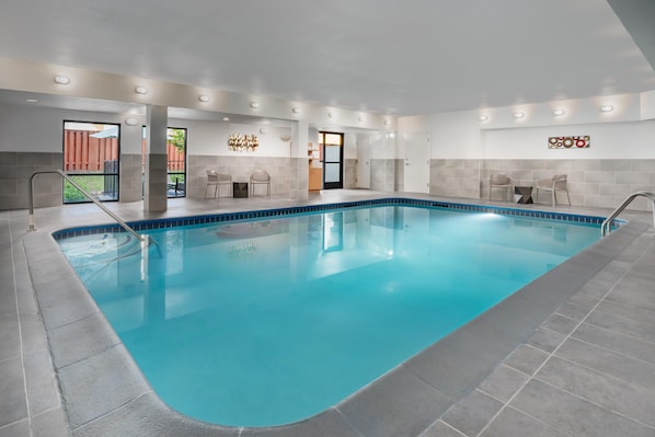 Una piscina interior con agua cristalina azul, paredes de azulejos y un diseño moderno.