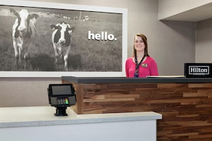 Un mostrador de recepción de hotel con una amplia fotografía blanco y negro de vacas y la palabra 'hello'.