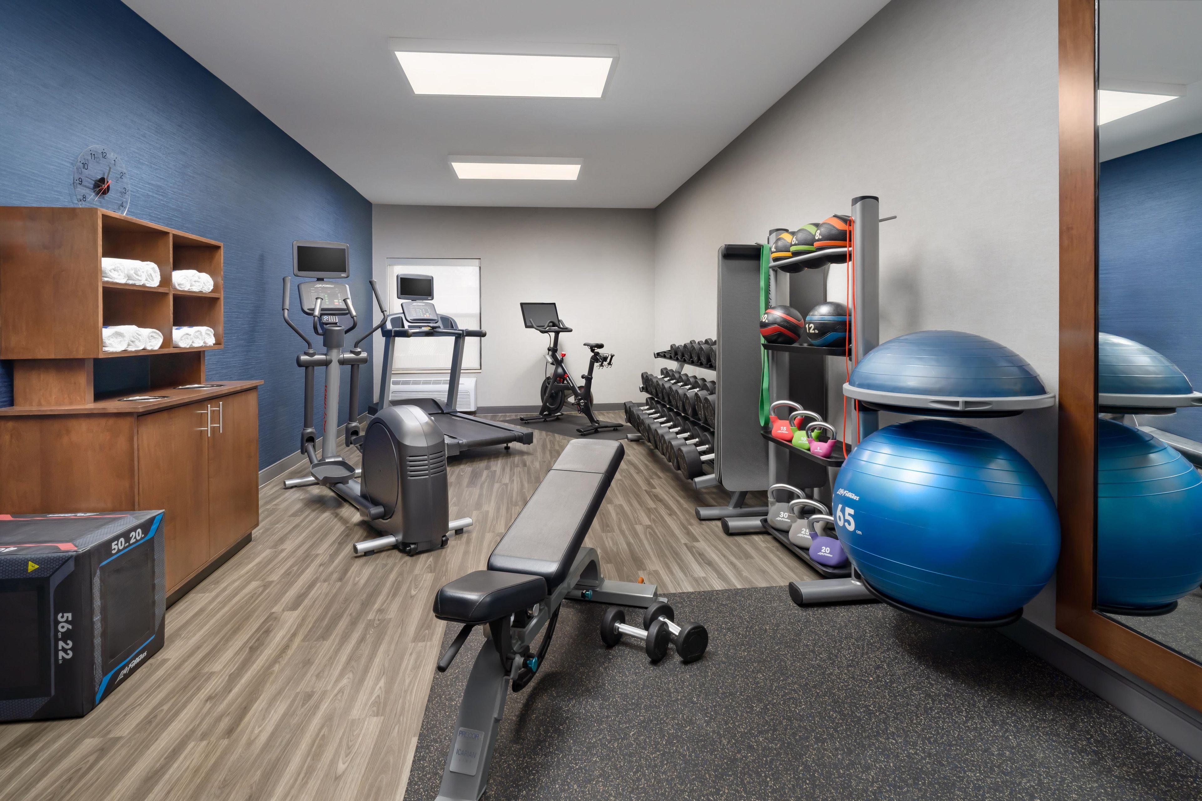 A gym with exercise equipment, a bench, a treadmill, and a mirror.