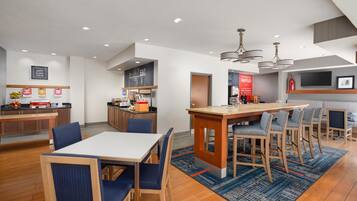 A modern kitchen with a central island, bar seating, and a dining area with blue upholstered chairs.