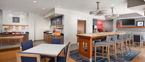 A modern kitchen with a central island, bar seating, and a dining area with blue upholstered chairs.