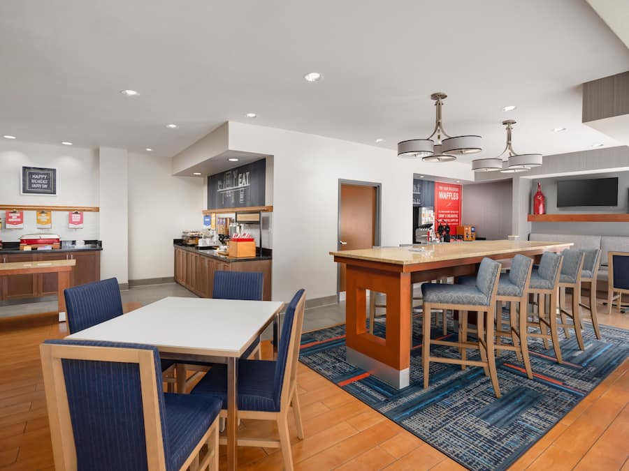 A modern kitchen with a central island, bar seating, and a dining area with blue upholstered chairs.