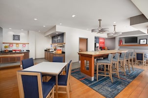 A modern kitchen with a central island, bar seating, and a dining area with blue upholstered chairs.