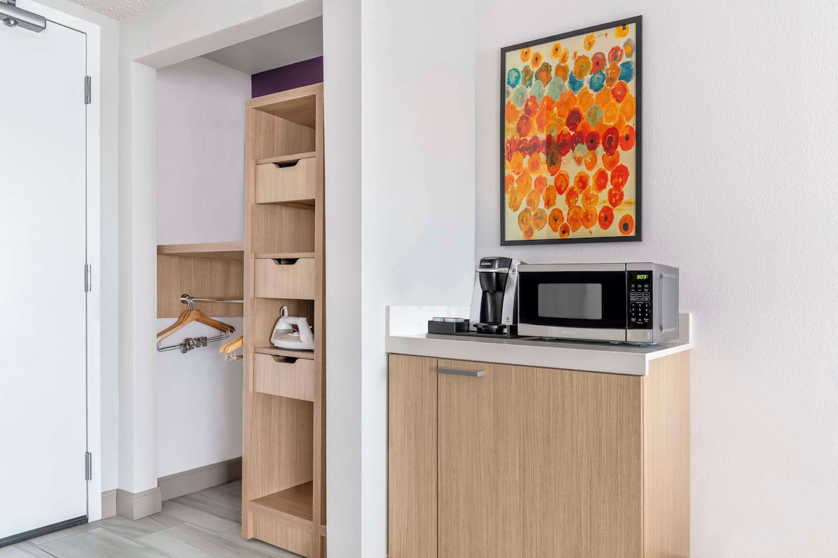A modern kitchen with a microwave, coffee maker, and wooden cabinets.