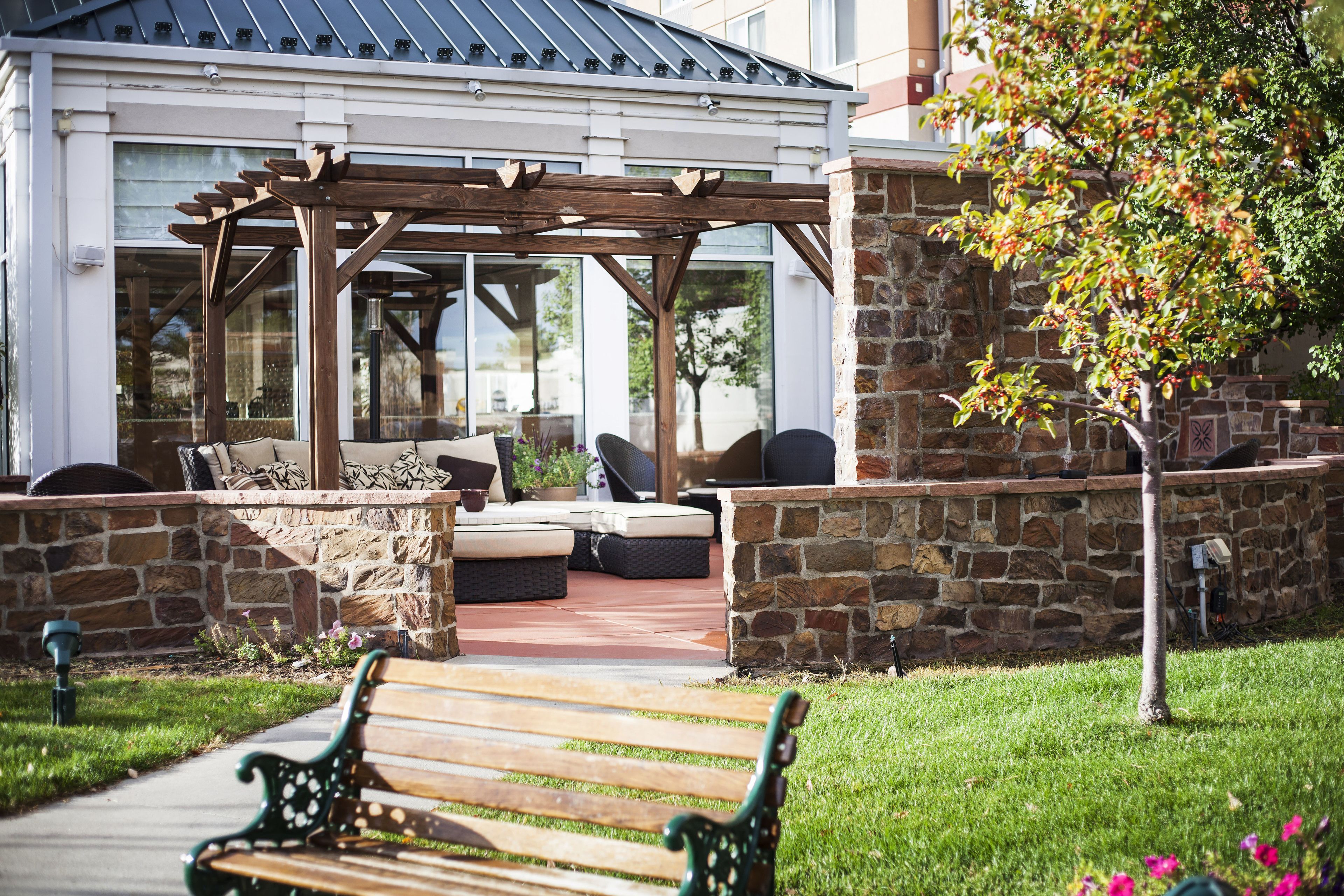 An outdoor patio area with a pergola, stone walls, and a bench.