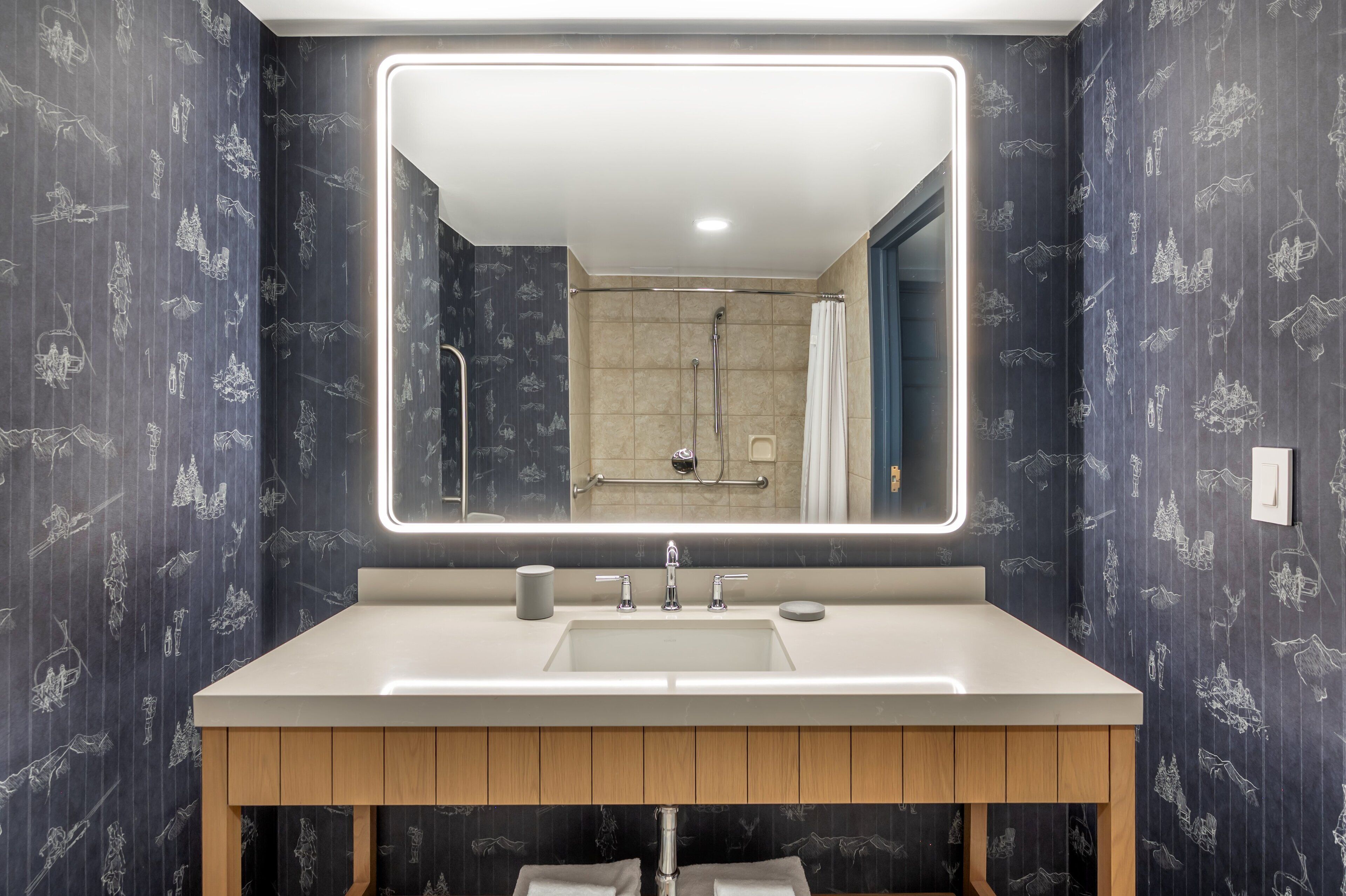 A modern bathroom with a large mirror, a sink, and a shower.