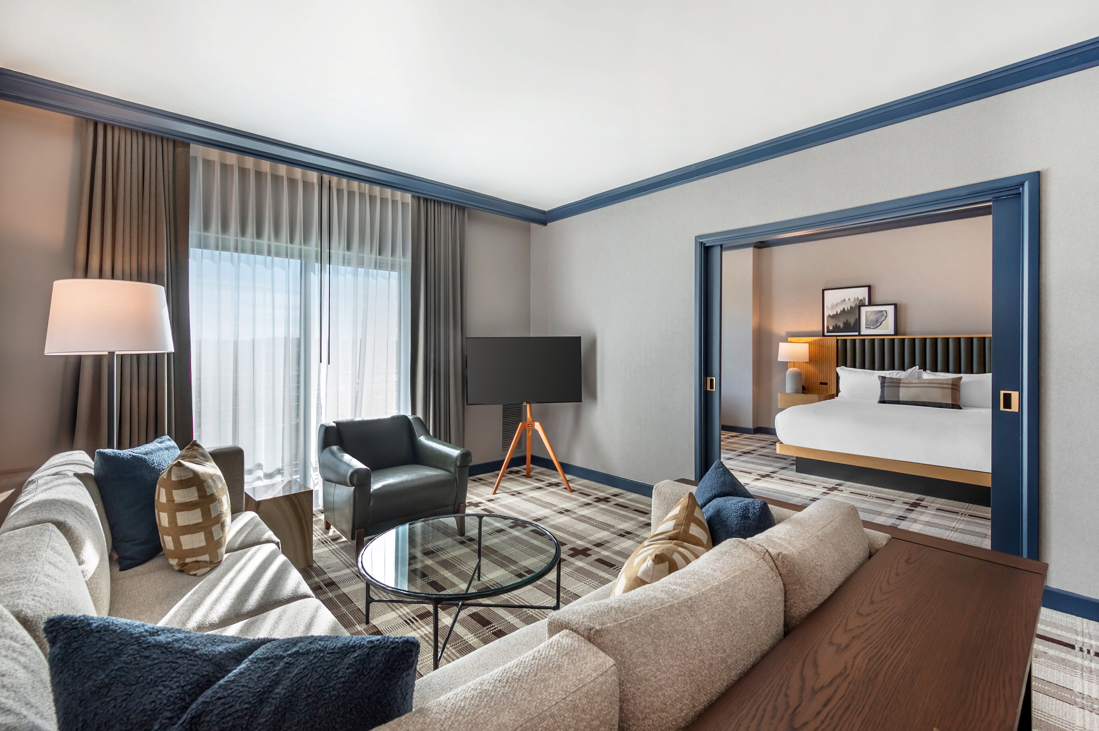 A hotel room with a large bed, a sofa, a coffee table, and a TV.