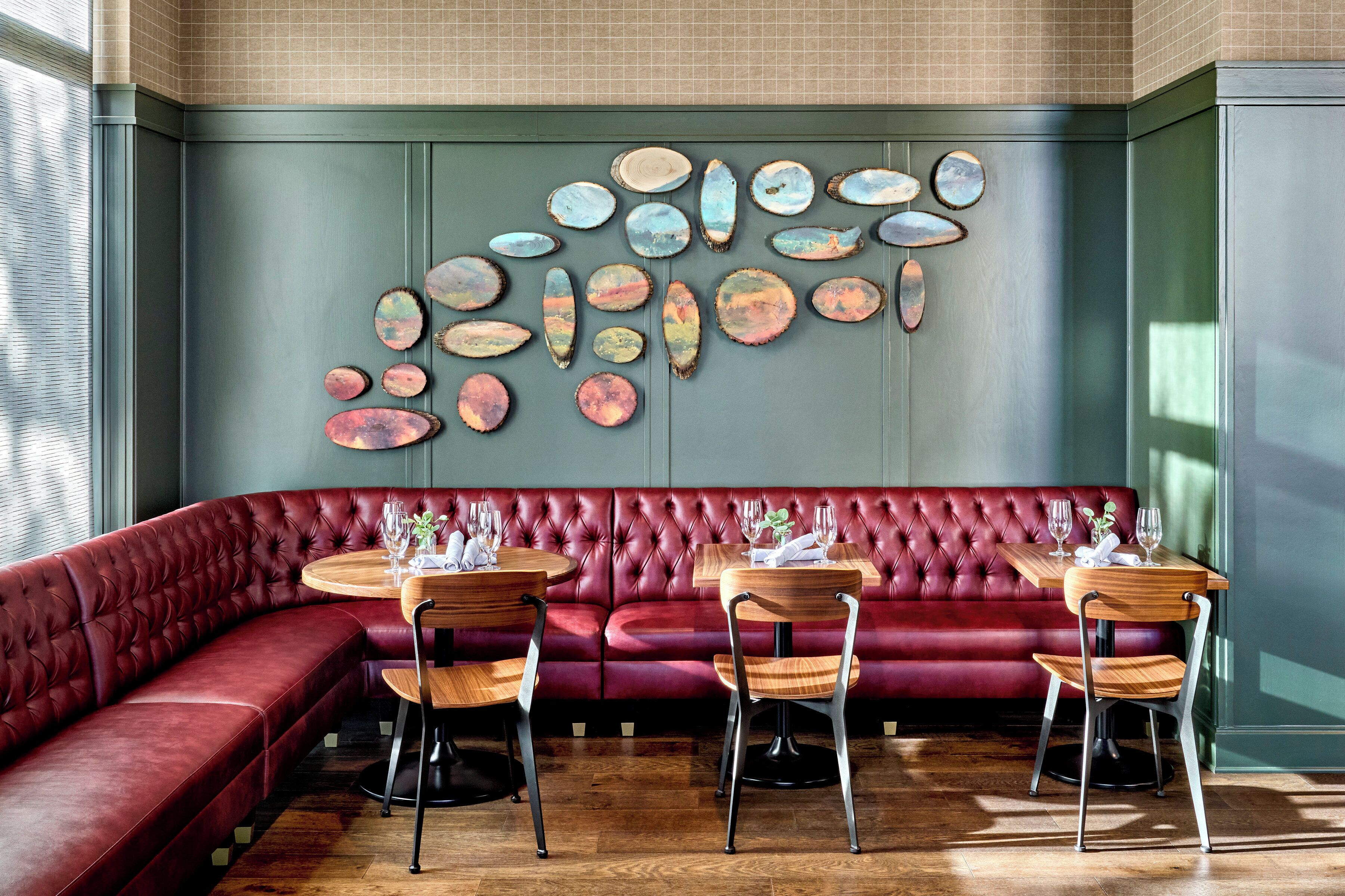 Un restaurant moderne avec des banquettes en cuir rouge, des tables et des chaises en bois.