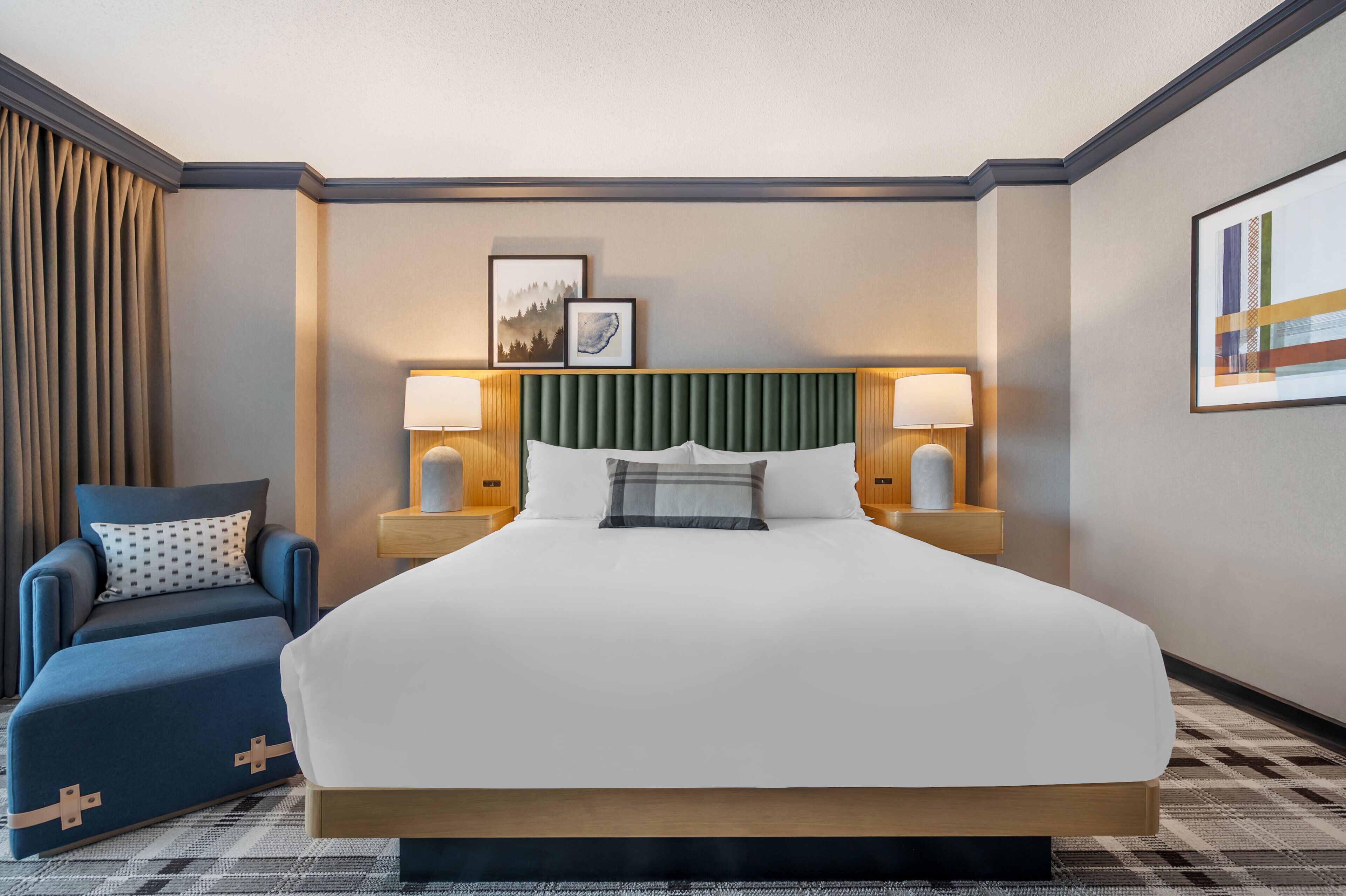 A hotel room with a large bed, a blue armchair, and two bedside lamps.