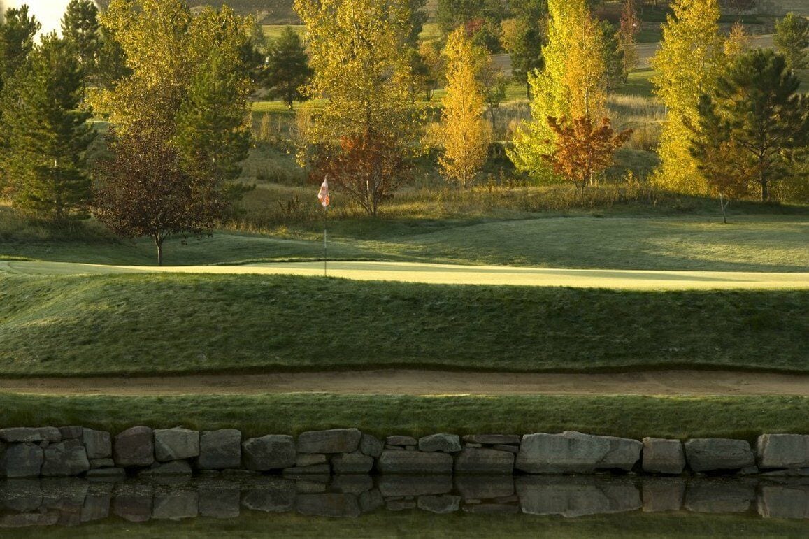 A golf course with a stone wall and a flag.