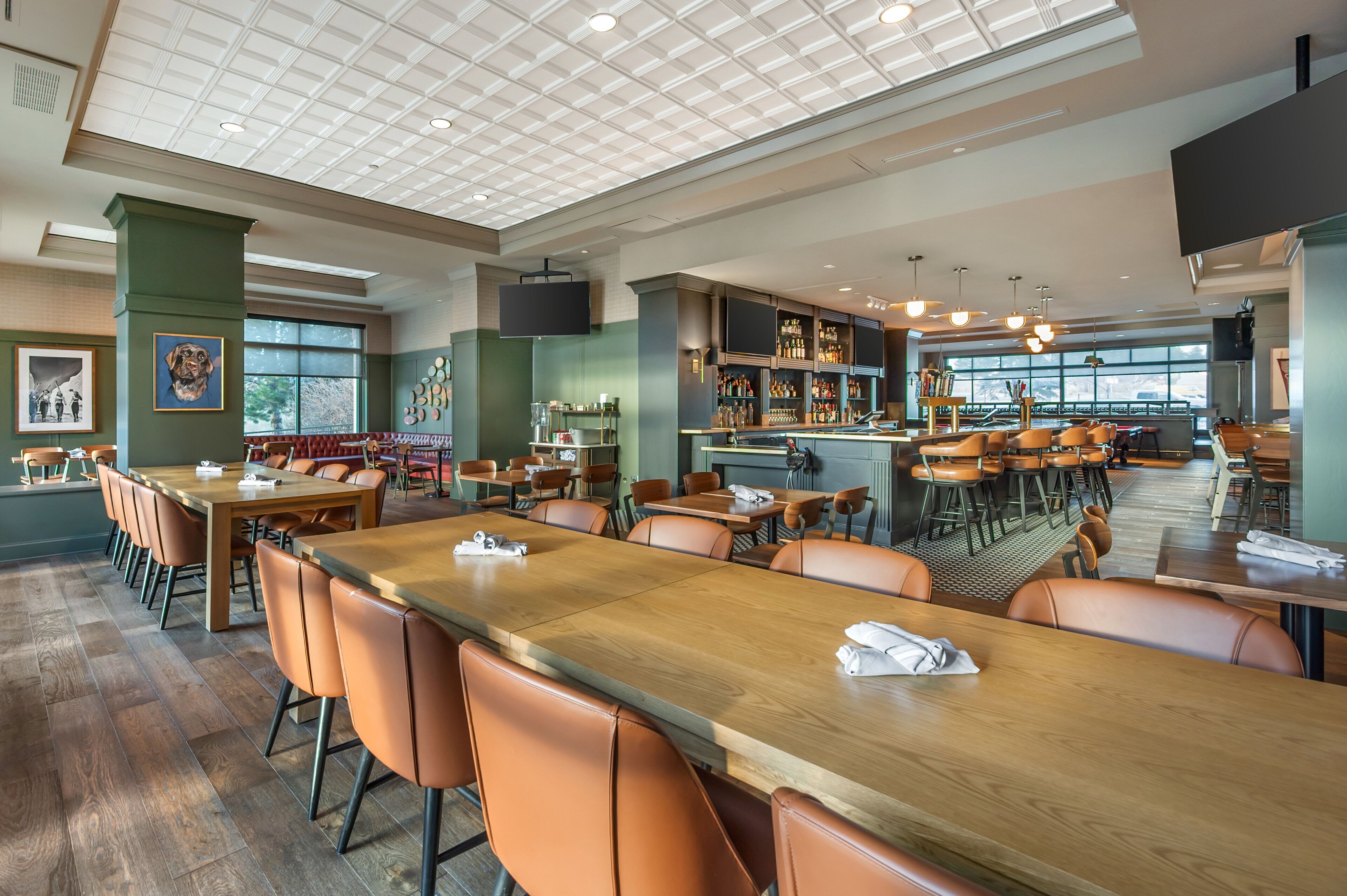 A spacious restaurant with high ceilings, wooden tables, and orange chairs.