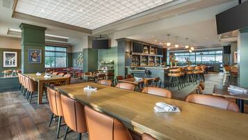 A spacious restaurant with high ceilings, wooden tables, and orange chairs.