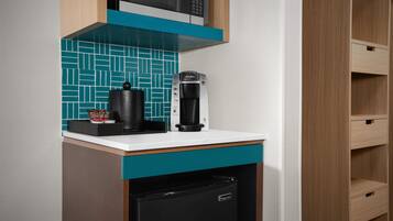 A kitchenette with a coffee maker, a microwave, and a refrigerator.