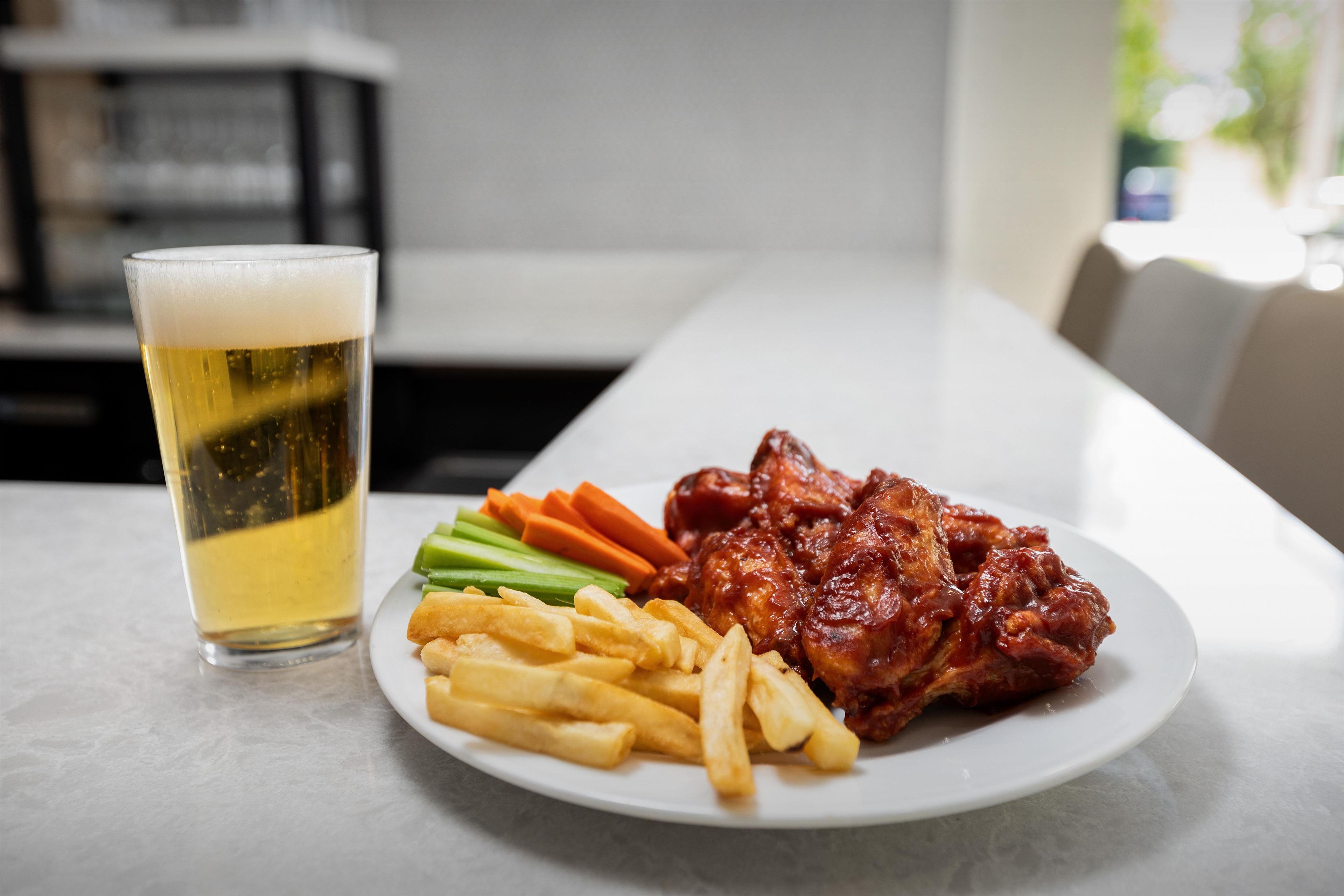 A plate of food with fries, vegetables, and meat, and a glass of beer on a table.