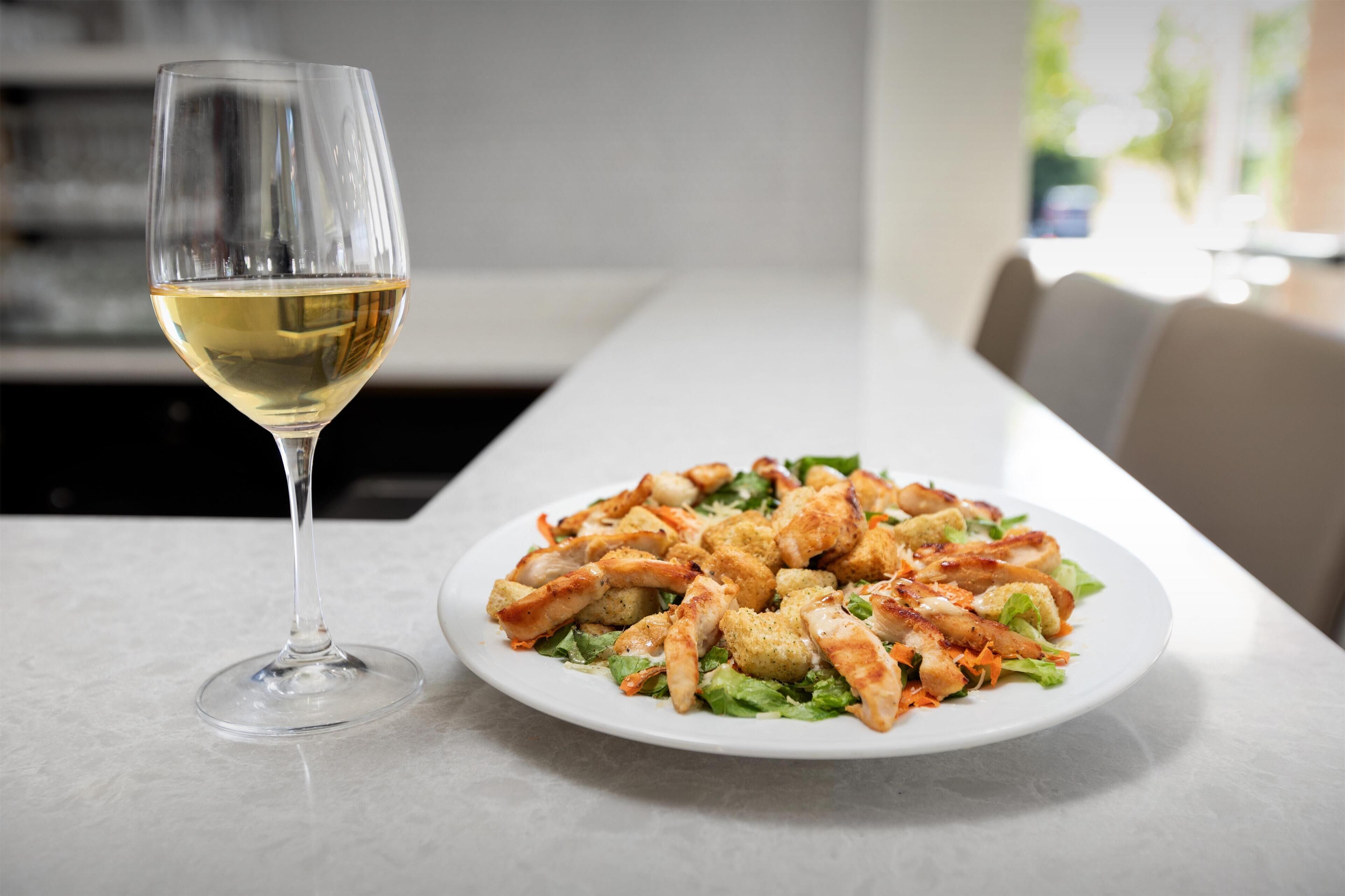 A dining table with a plate of food and a wine glass.