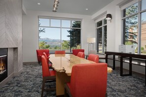 A conference room with a large table, red chairs, a fireplace, and large windows offering a mountain view. - Hilton Garden Inn Colorado Springs North Air Force Academy (Colorado Springs)